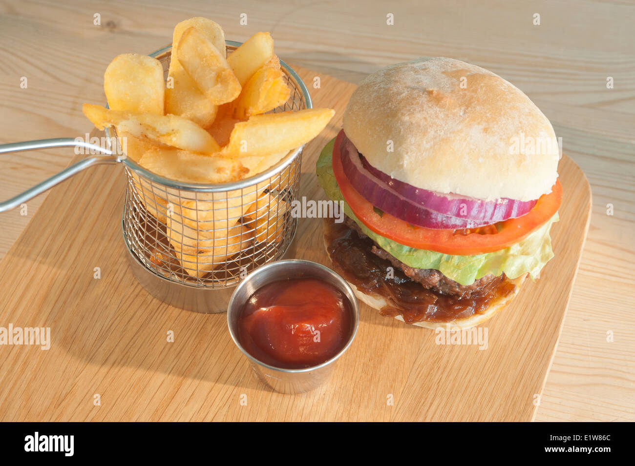 Classic burger and salad with side order of French fries or chips and tomato ketchup on a wooden plate Stock Photo