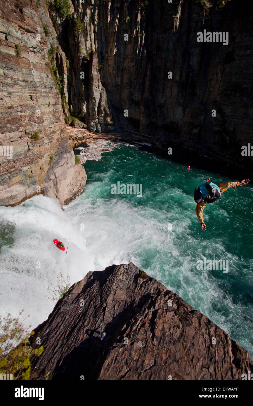 A male kayaker runs leap of faith, a 30 foot waterfall while a cliff jumper jumps from 70ft on the Upper Elk River, Fernie, BC Stock Photo