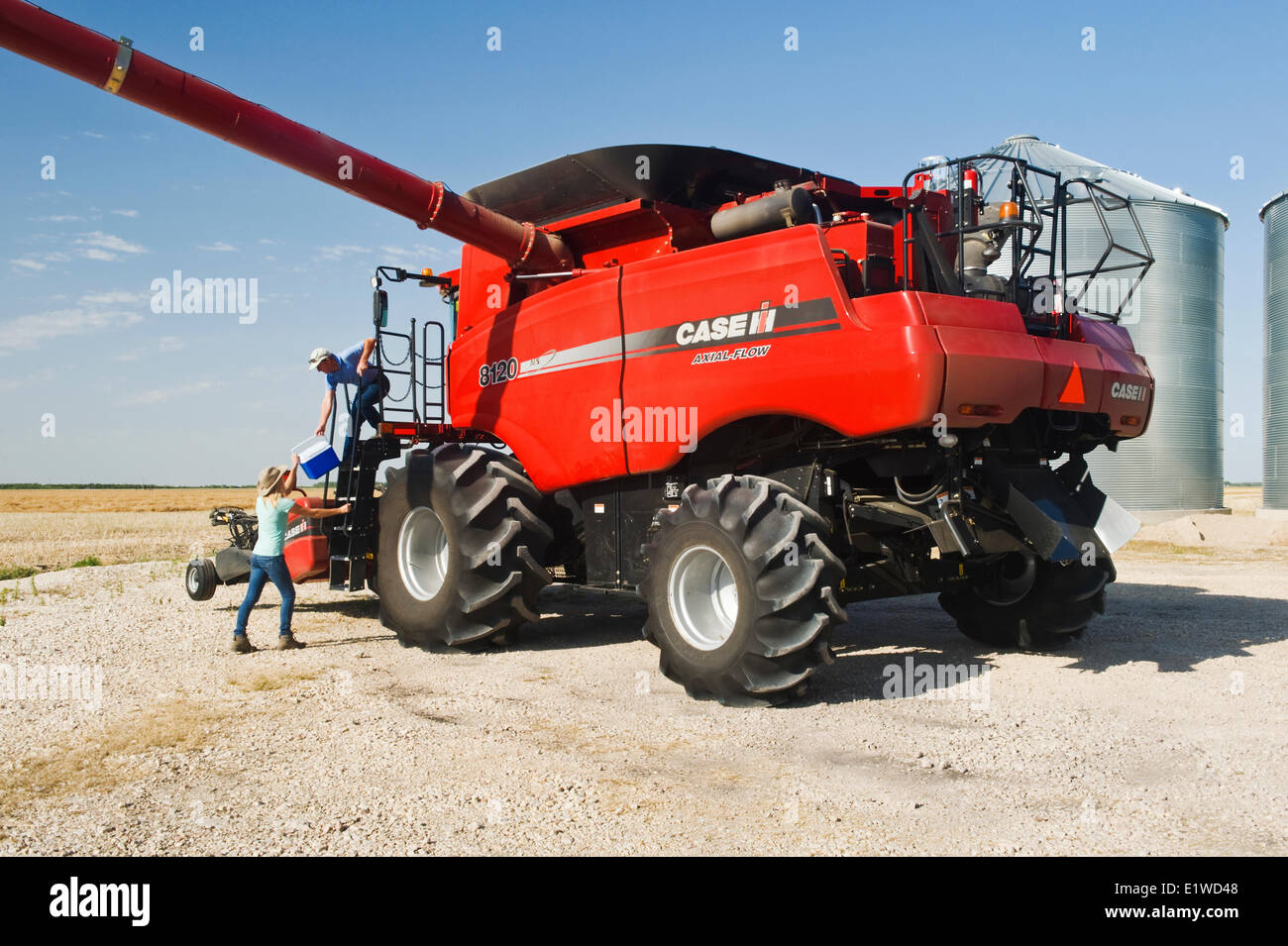 a teenage farm girl brings lunch to her father on the deck of a combine during the harvest, near Dugald,  Manitoba, Canada Stock Photo