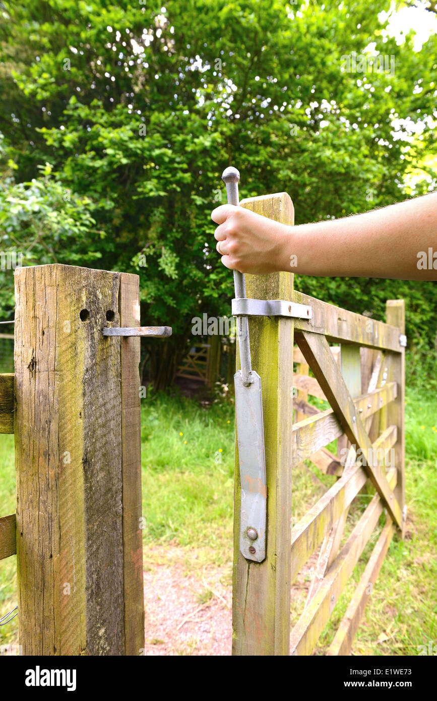 hand holding a gate open in the countryside Stock Photo