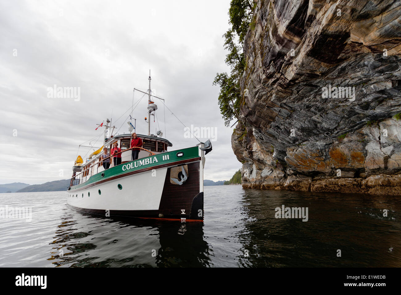 The Columbia III noses in and under a large overhanging cliff known as the deep sea bluffs for guests to take pictures while on Stock Photo