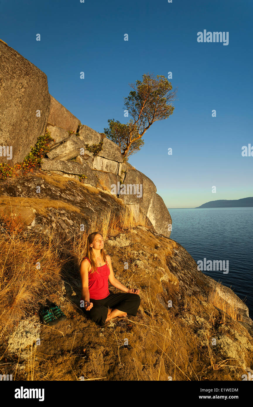 A young woman meditates along the bluffs Stillwater near Powell River.  Stillwater Bluffs The Sunshine Coast ,British Columbia Stock Photo