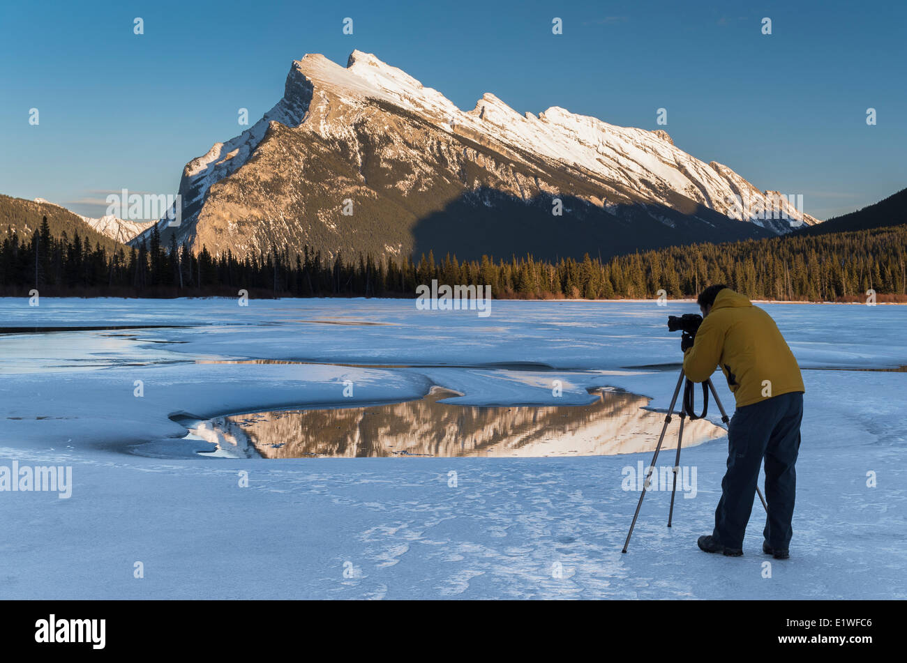 Photographer composing a photograph of Mount Rundle on frozen Vermilion Lakes in winter in Banff National Park, Alberta, Canada. Stock Photo
