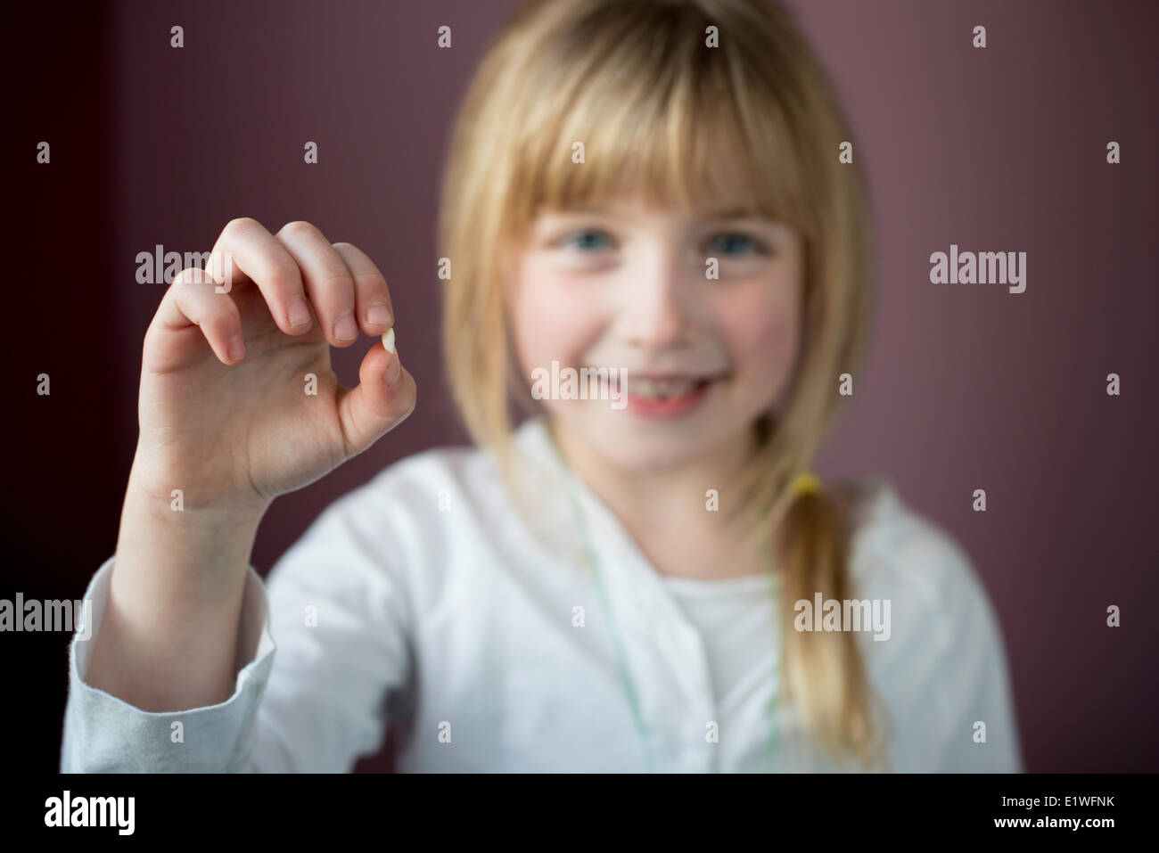 Smiling little girl showing her first loose tooth with focus on the tooth Stock Photo