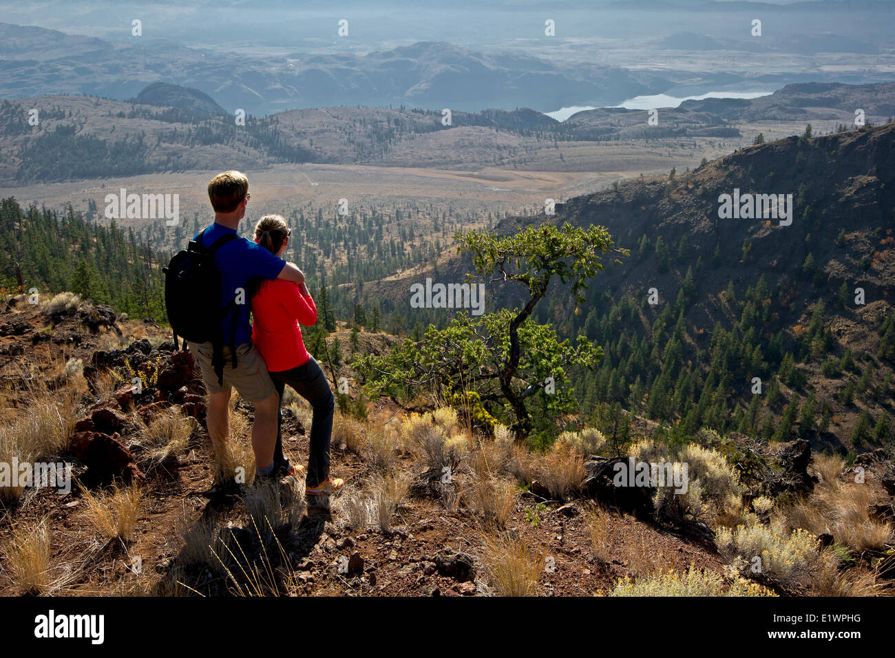 A young couple stop to enjoy the view while hiking the Dewdrop trail in the Lac du Bois protected grasslands above Kamloops Stock Photo