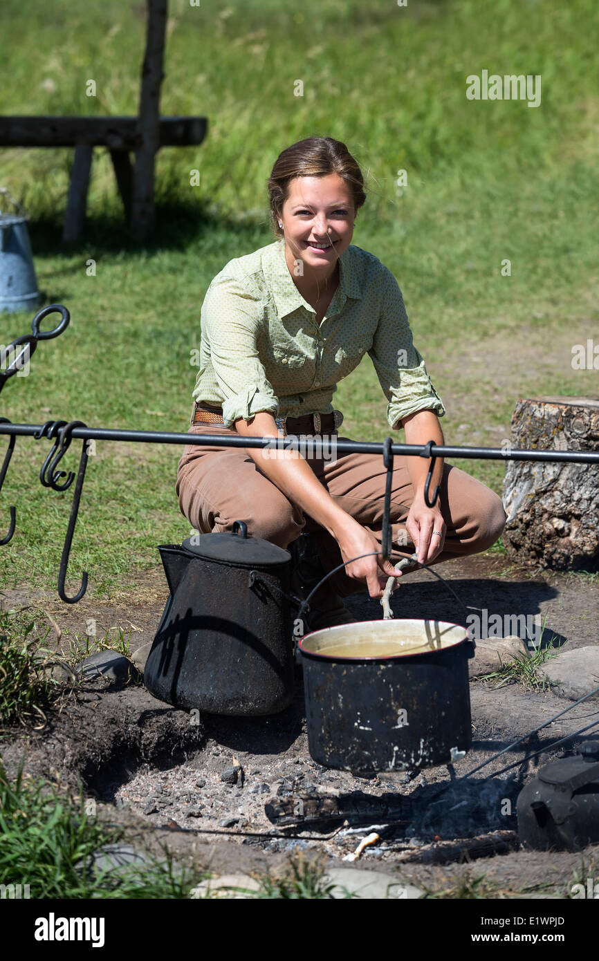 Pioneer woman cooking at an outdoor campsite, Bar U Ranch National