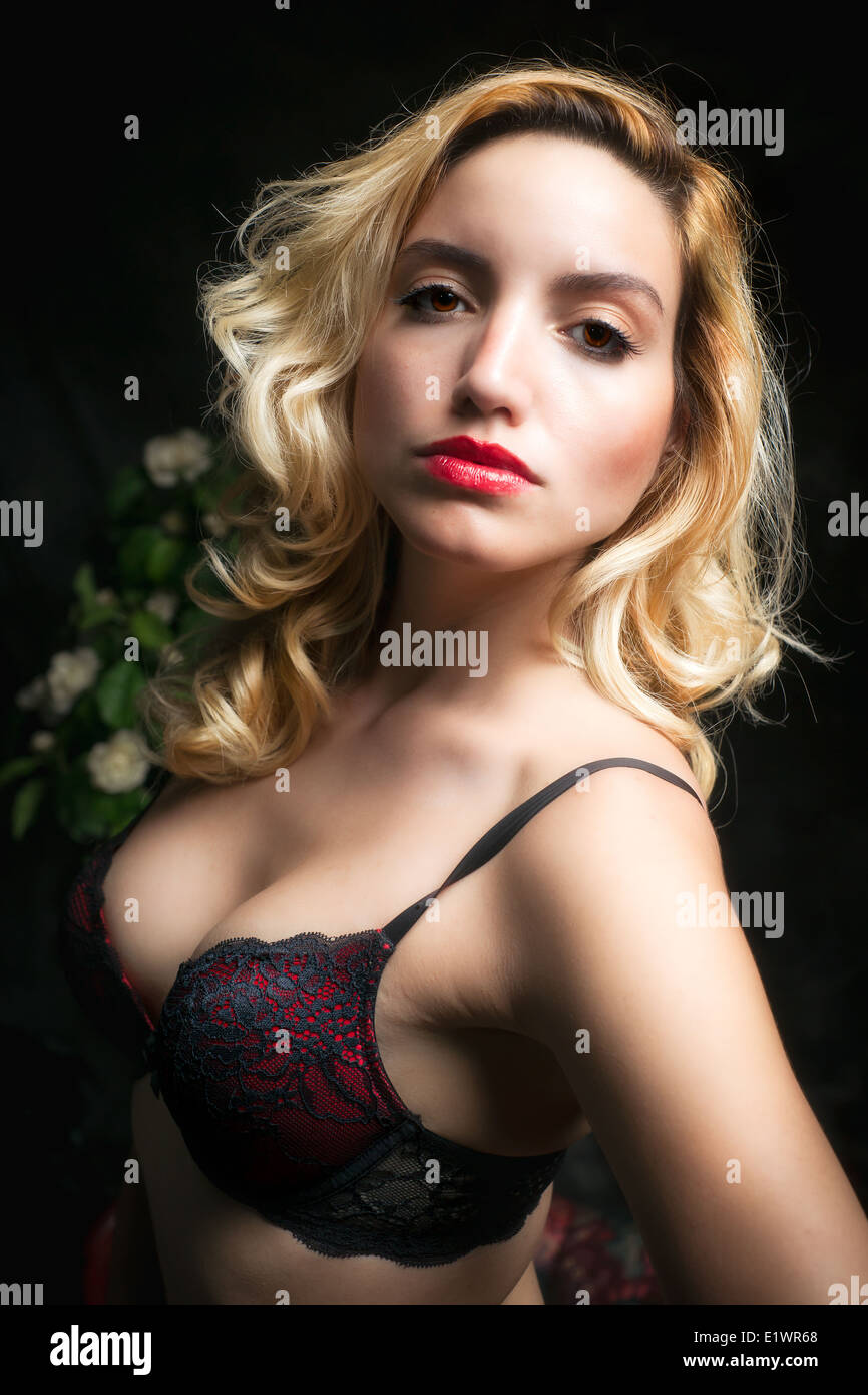A young, beautiful and sexy blonde woman in a red lace bra stares  seductivly into the camera Stock Photo - Alamy