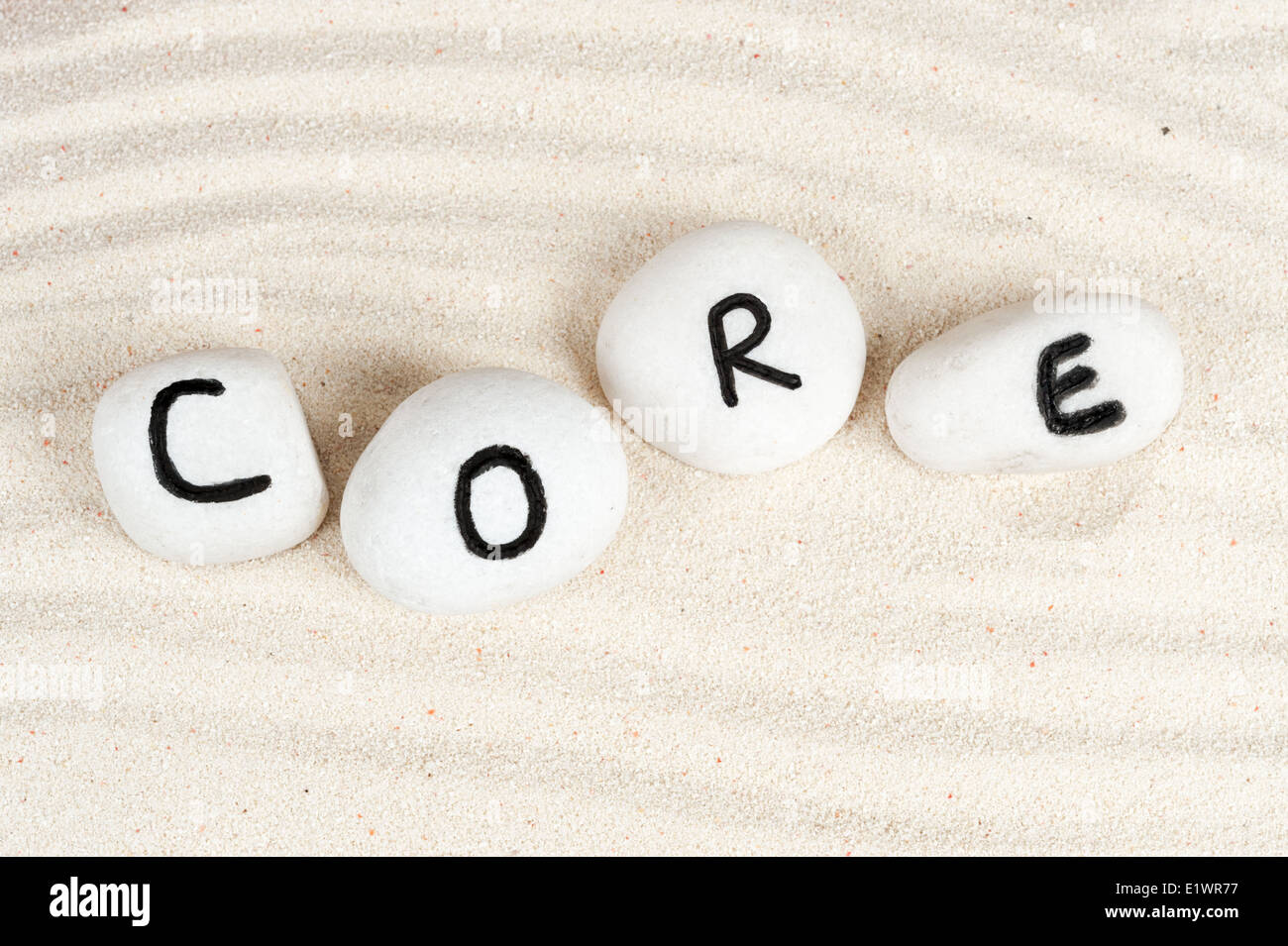 Core word on group of stones with sand as background Stock Photo