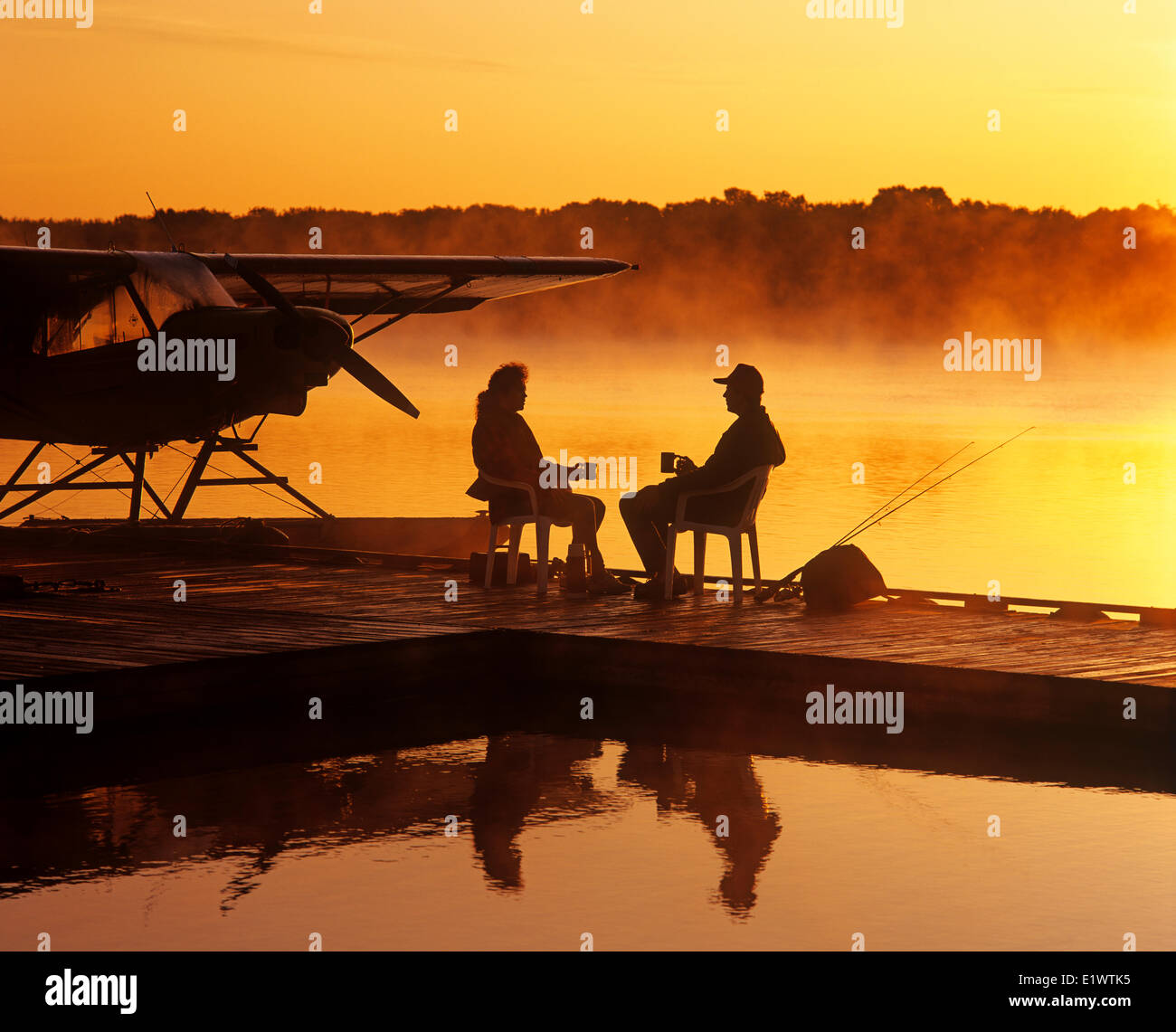 a couple relaxes on a float plane dock, Manitoba, Canada Stock Photo