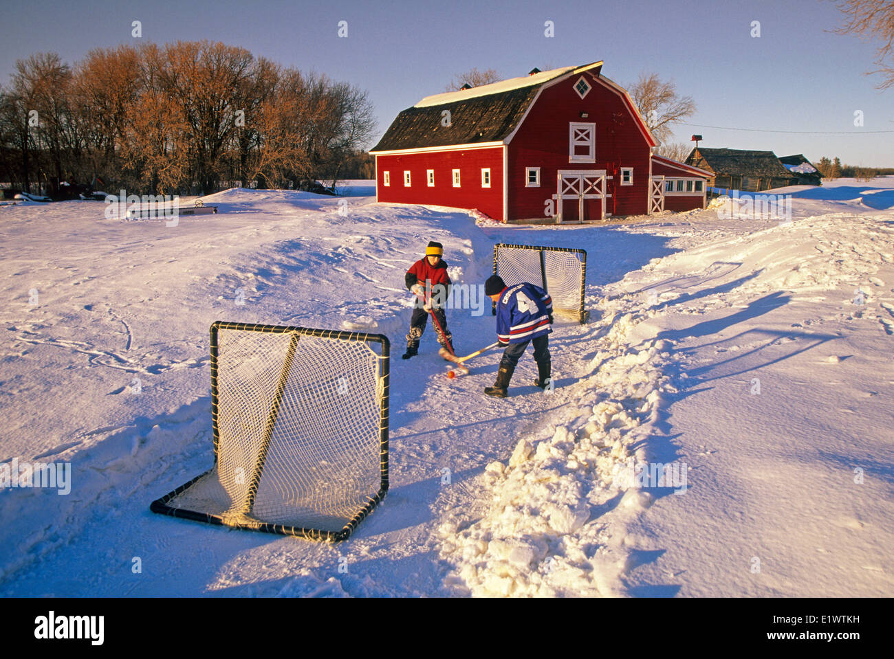 boys playing hockey in front of a red barn , near Oakbank, Manitoba