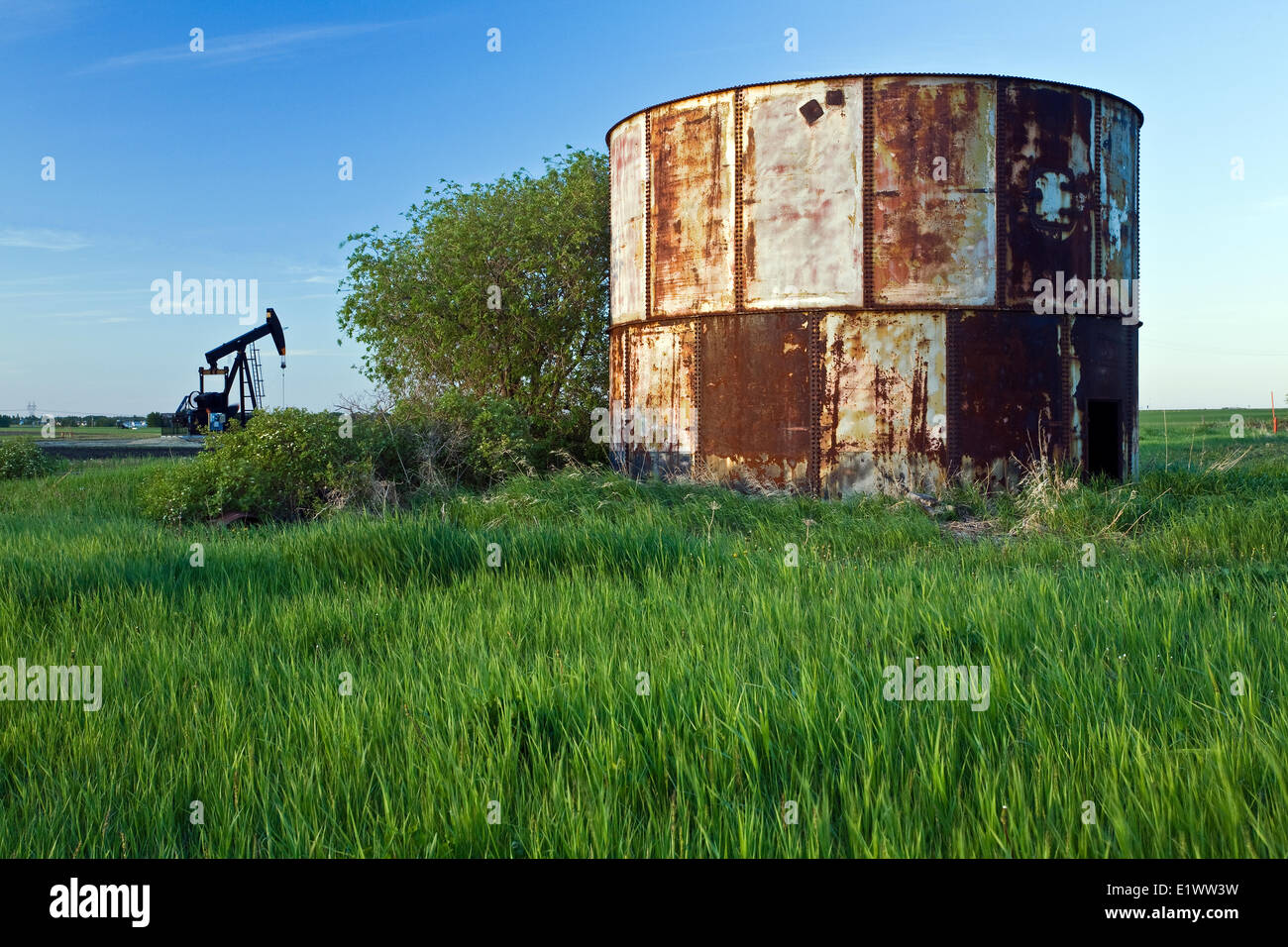 Abandoned oil storage container and working pumpjack, Alberta, Canada. Stock Photo