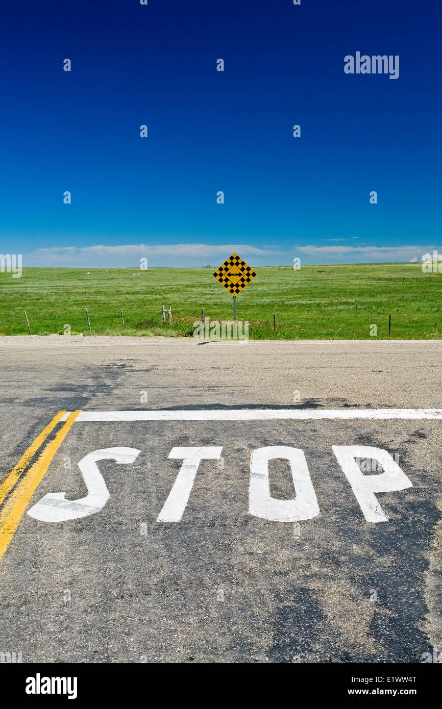 Stop sign painted on rural road with direction sign, south Alberta, Canada. Stock Photo