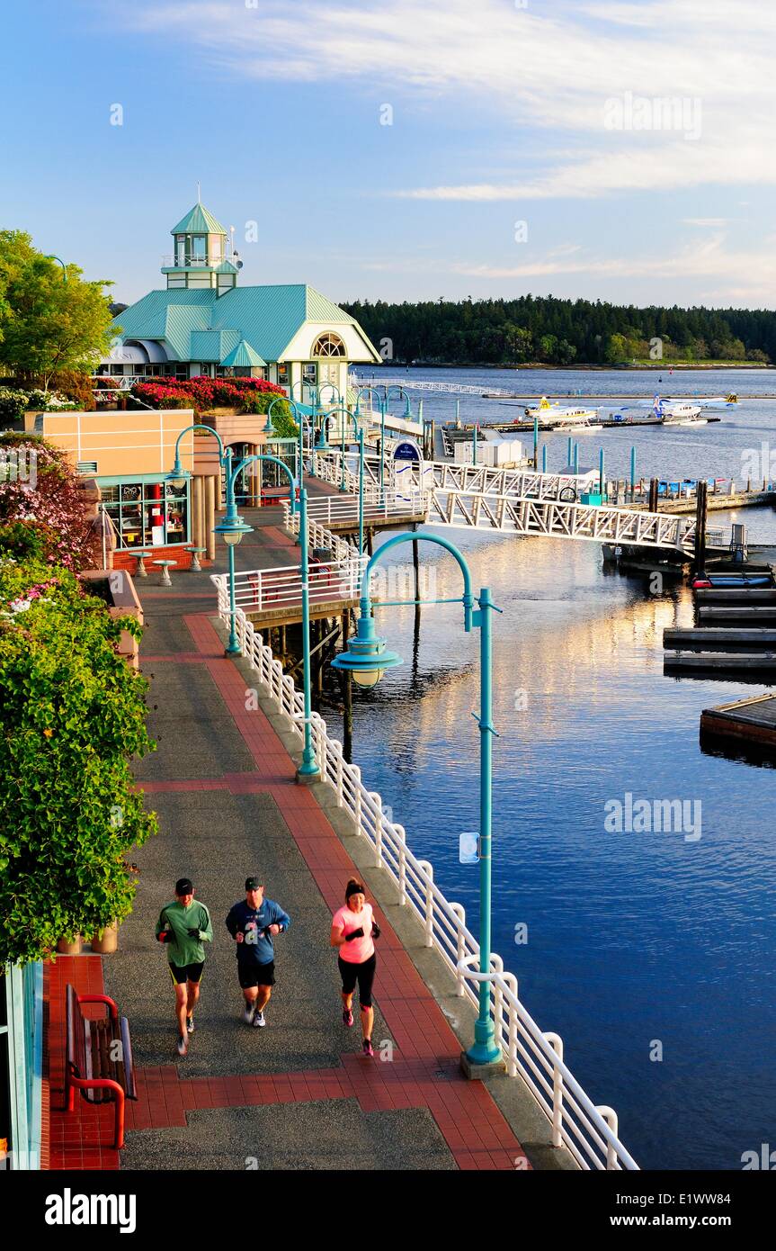 Joggers running along the Pioneer Waterfront Plaza and walkway in the harbour in Nanaimo, BC. Stock Photo