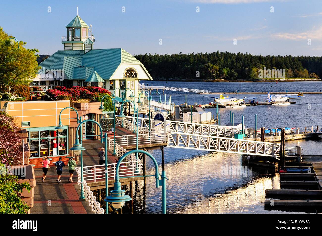 Joggers running along the Pioneer Waterfront Plaza and walkway in the harbour in Nanaimo, BC. Stock Photo