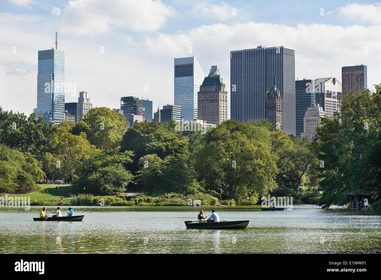 Lush Central Park set against New York City skyscrapers. In the foreground is the Lake where parkgoes can rent row boats relax Stock Photo