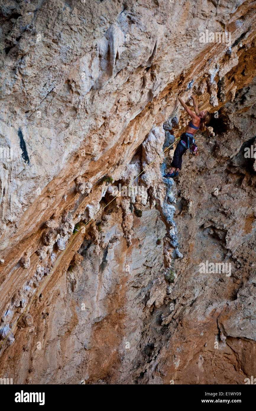 A strong female climber ascends through the limestone tufas of Morgan 7b+, Sitkati Cave, Kalymnos, Greece Stock Photo