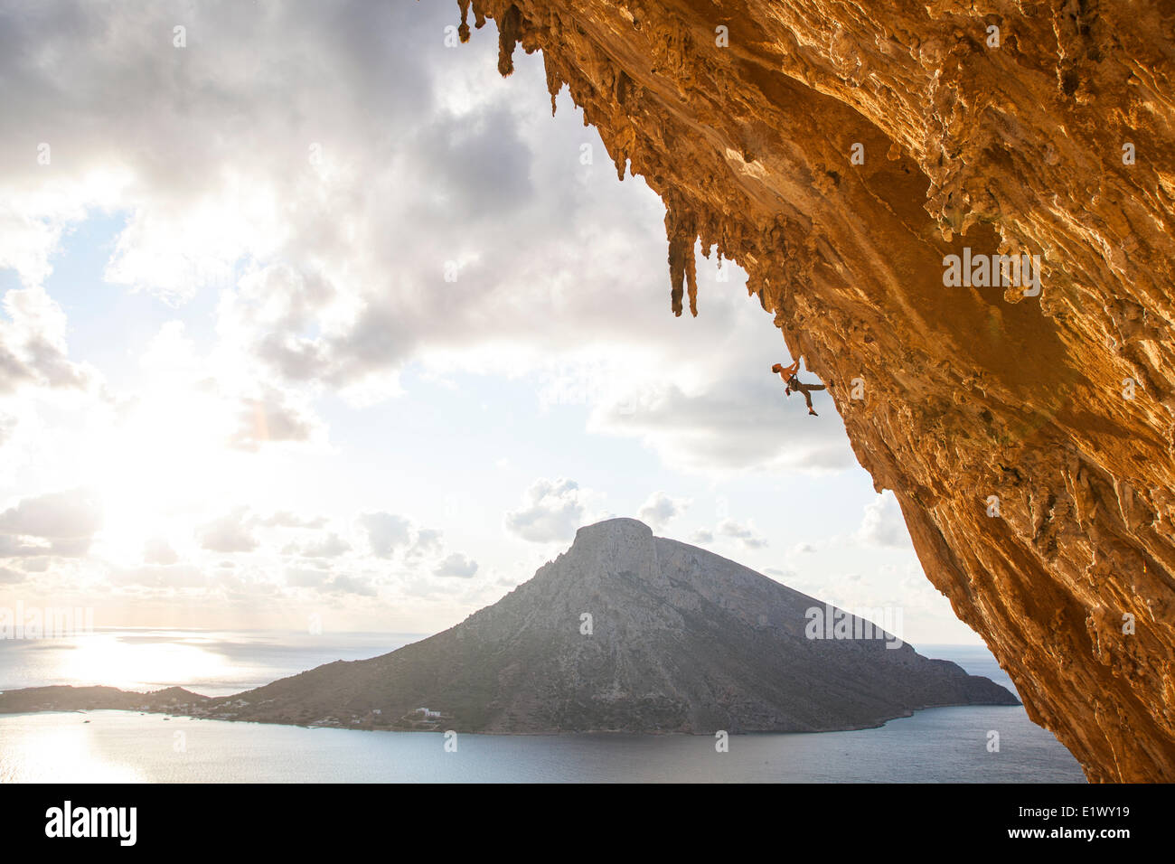 A male climber ascends through the wild limestone rock formations in the enormous cave of Grand Grotto, Kalymnos, Greece Stock Photo