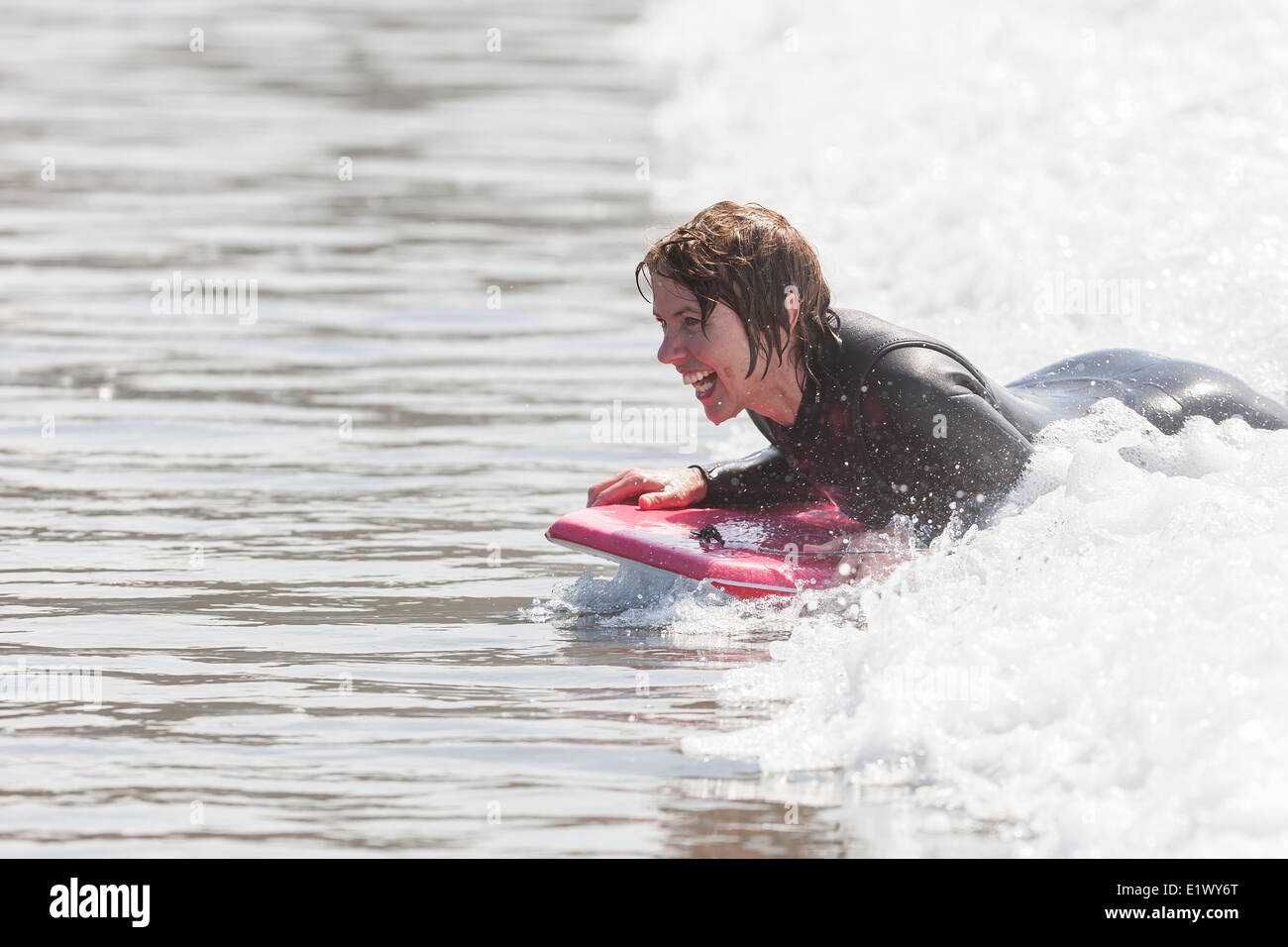 A mature woman expereinces the fun body surfing on Chesterman Beach near Tofino.  Pacific Rim Vancouver Island British Columbia Stock Photo