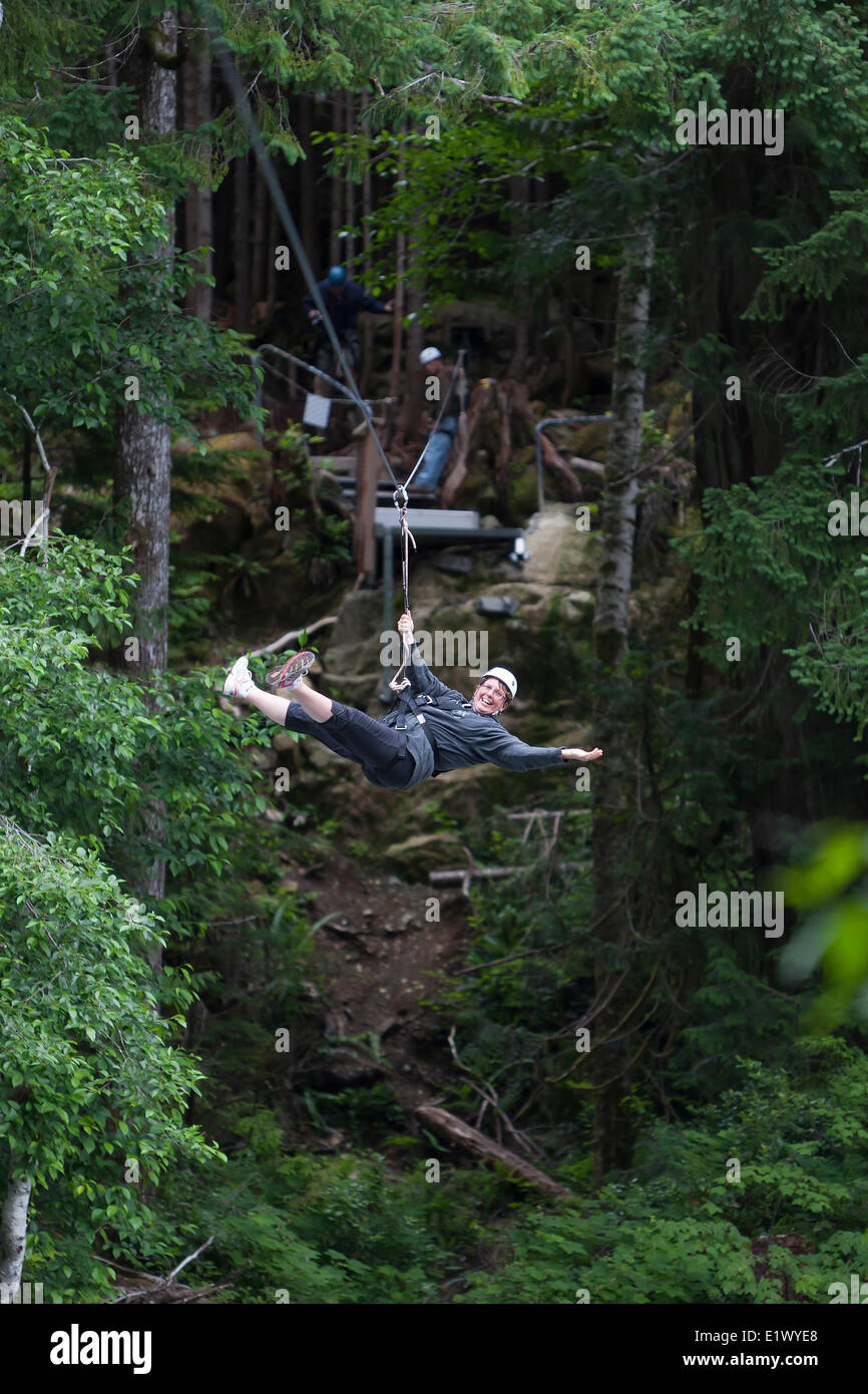 A mature woman speeds along the West Coast Wild Adventures Zipline which overlooks the Kennedy Canyon.  Highway 4 Vancouver Stock Photo