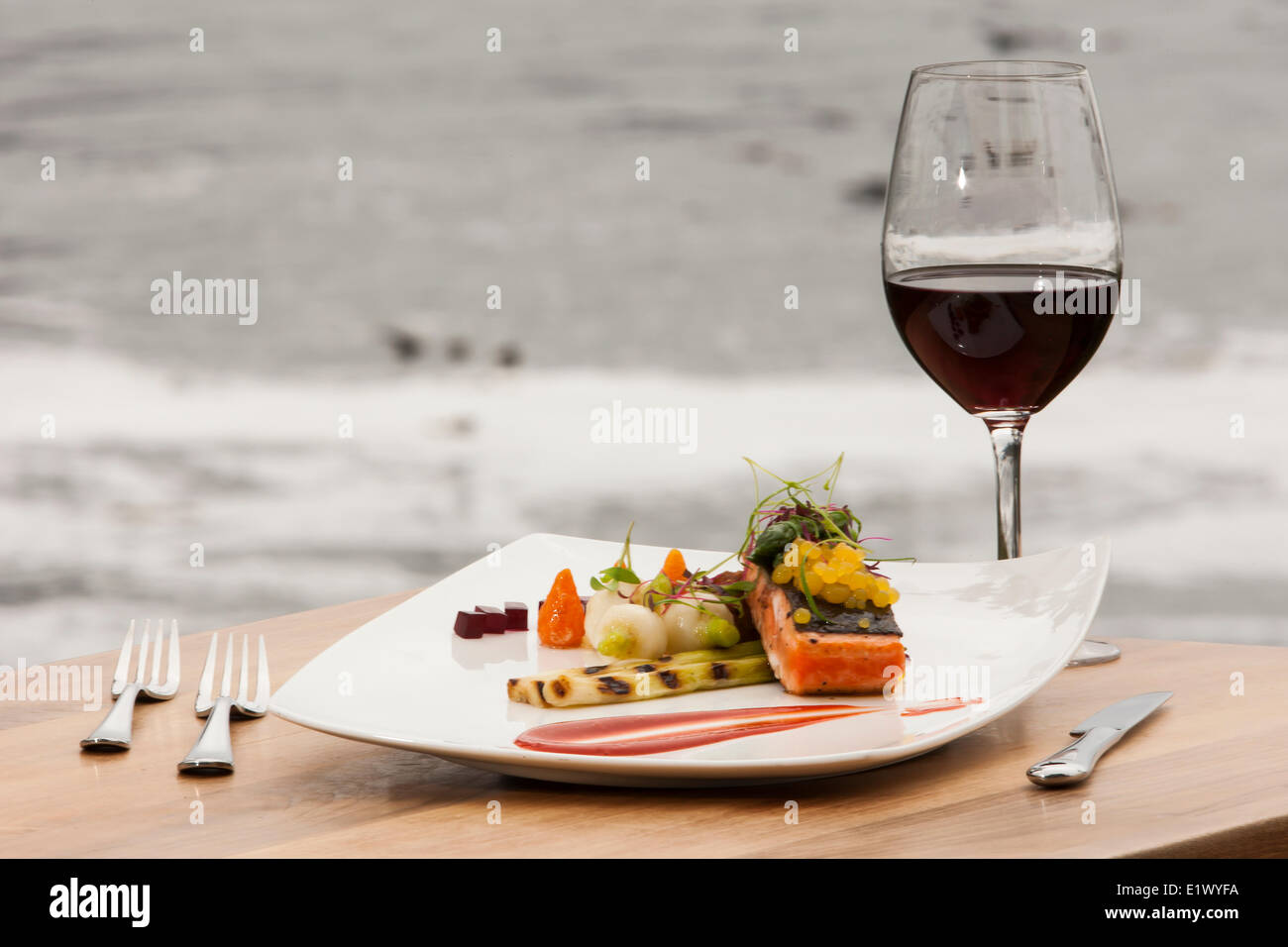 A single serving Salmon main course with accompanying red wine served up fresh at the Black Rock Resort in Ucluelet.  Ucluelet Stock Photo