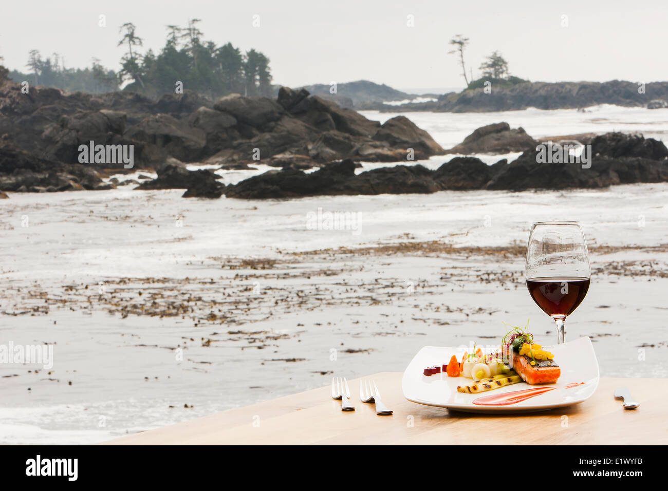 A single serving Salmon main course with accompanying red wine overlooks the ocean swells surrounding the Black Rock Resort in Stock Photo