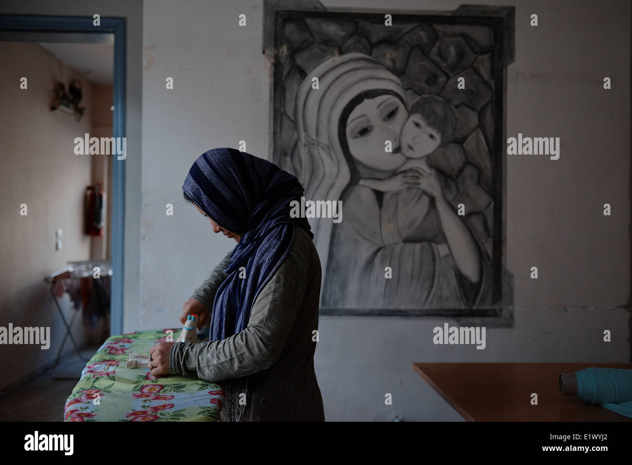 A muslim Syrian woman irons clothes in a refugee guesthouse in Thessaloniki, Greece Stock Photo