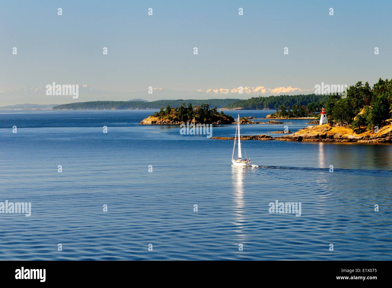 A sailboat passes Portlock Point Light Station on Prevost Island in Swanson Channel in British Columbia. Stock Photo