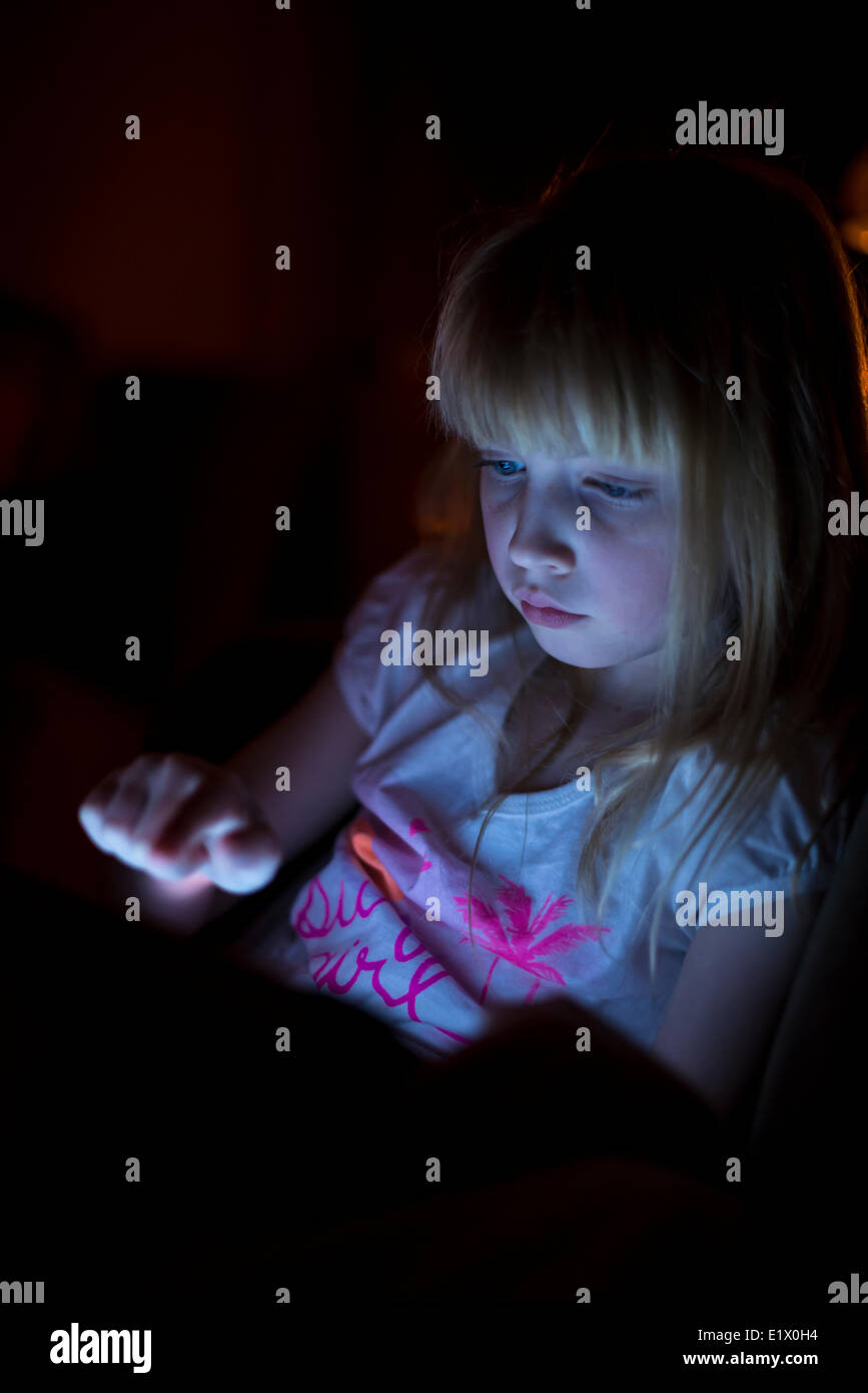 Little girl playing with tablet at night. Stock Photo
