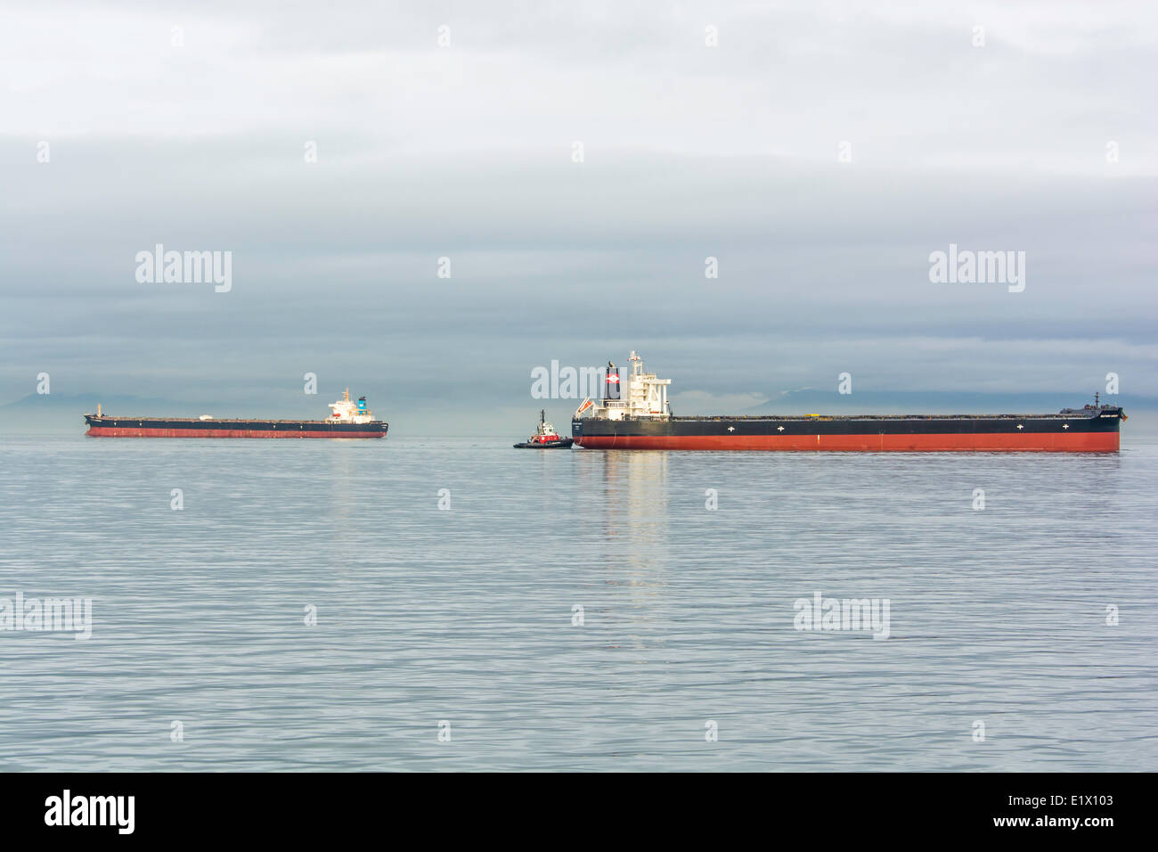 Freighter being moved to the dock by tugboat, British Columbia, Canada Stock Photo