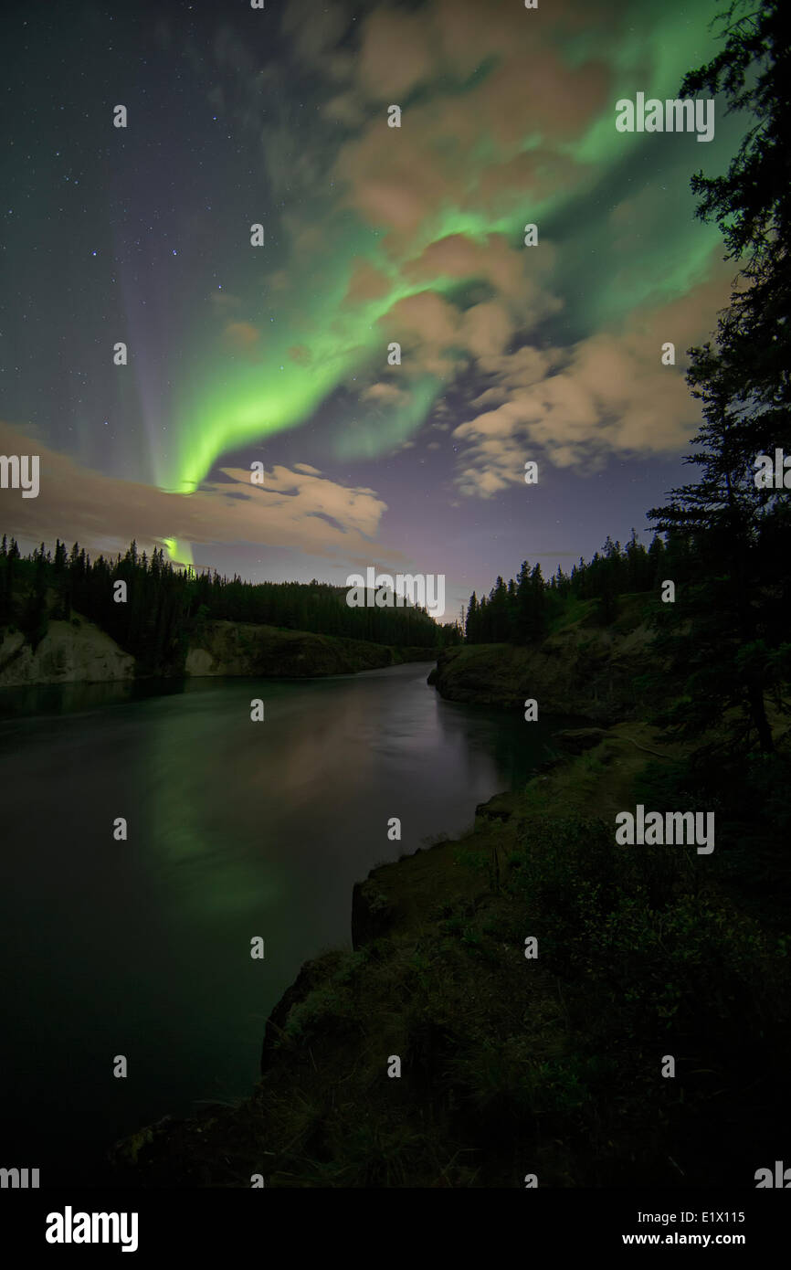 The aurora borealis or northern lights light up the night sky over top the Yukon River as it flows through Miles Canyon Stock Photo