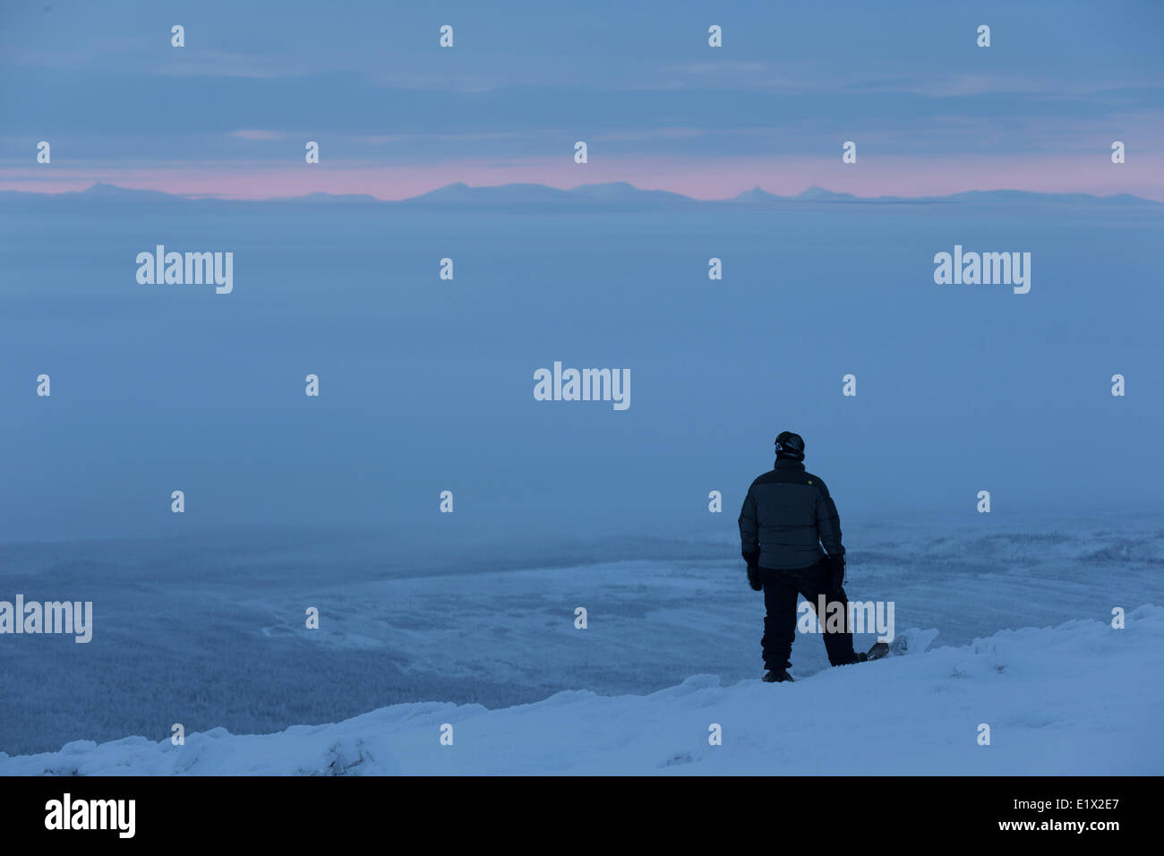 Person standing on the top of Crow Mountain while covers the valley below, northern Yukon. Stock Photo