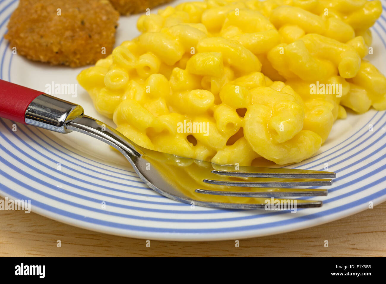 Close view of a meal of chicken nuggets with macaroni and cheese on a plate with fork. Stock Photo