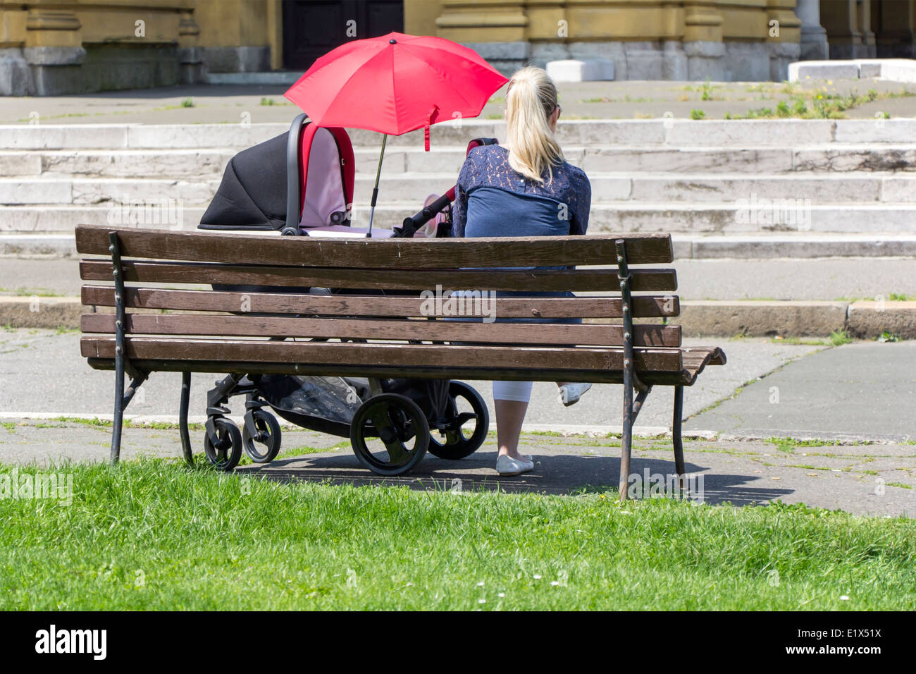 Mothers and baby in stroller, sitting on bench Stock Photo