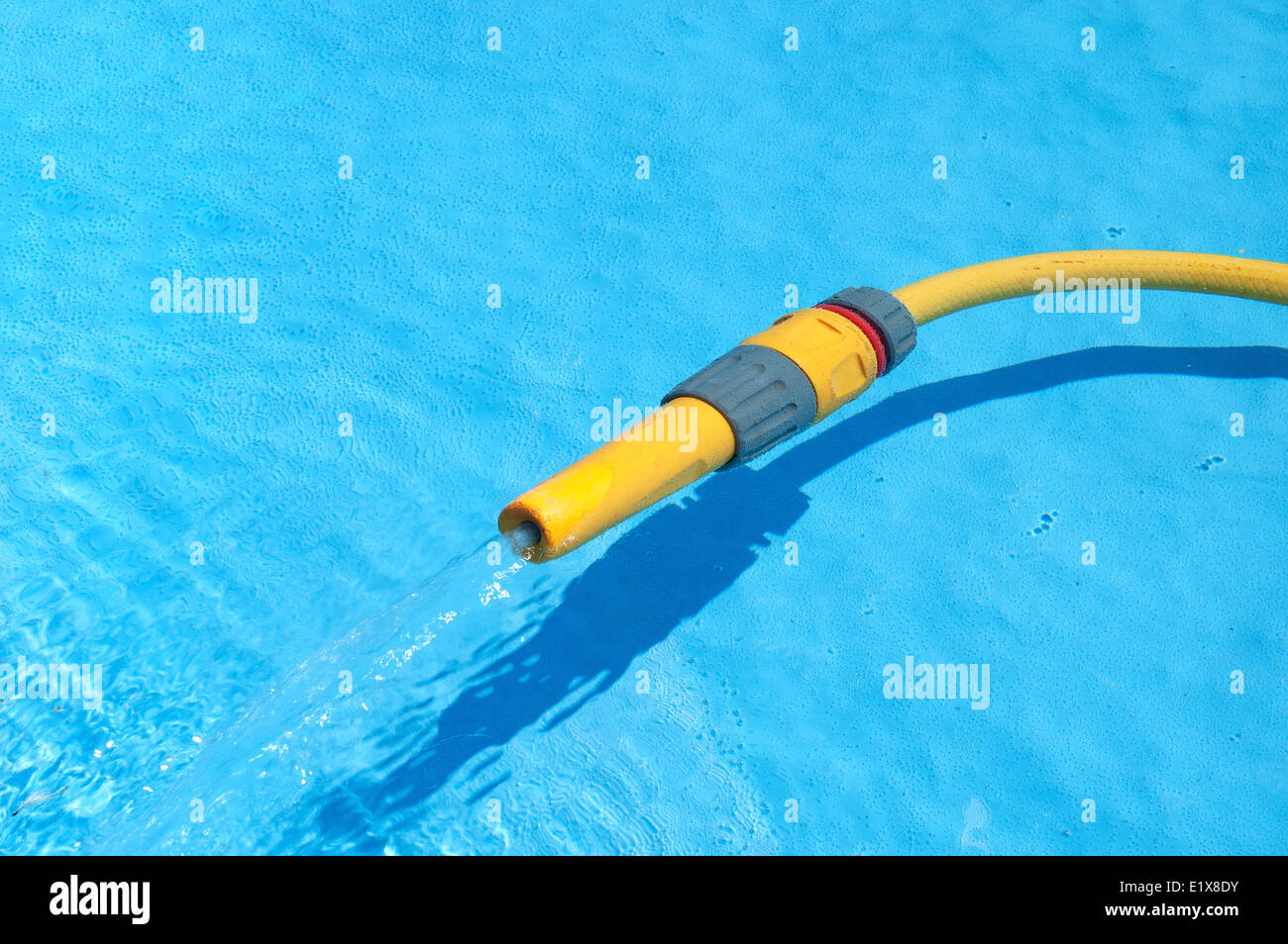 a hosepipe filling up a pool Stock Photo
