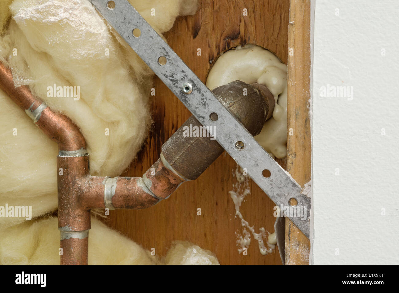 section of home wall cut open to reveal pipes for a plumbing repair Stock Photo