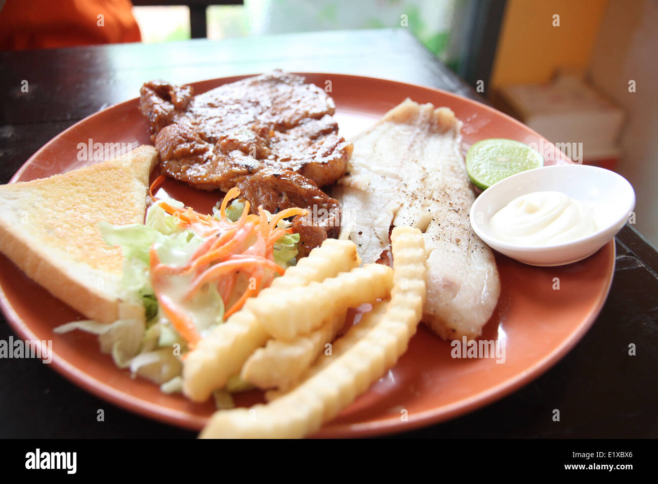 grilled pork steak with french fries and toast on the table in restaurant. Stock Photo