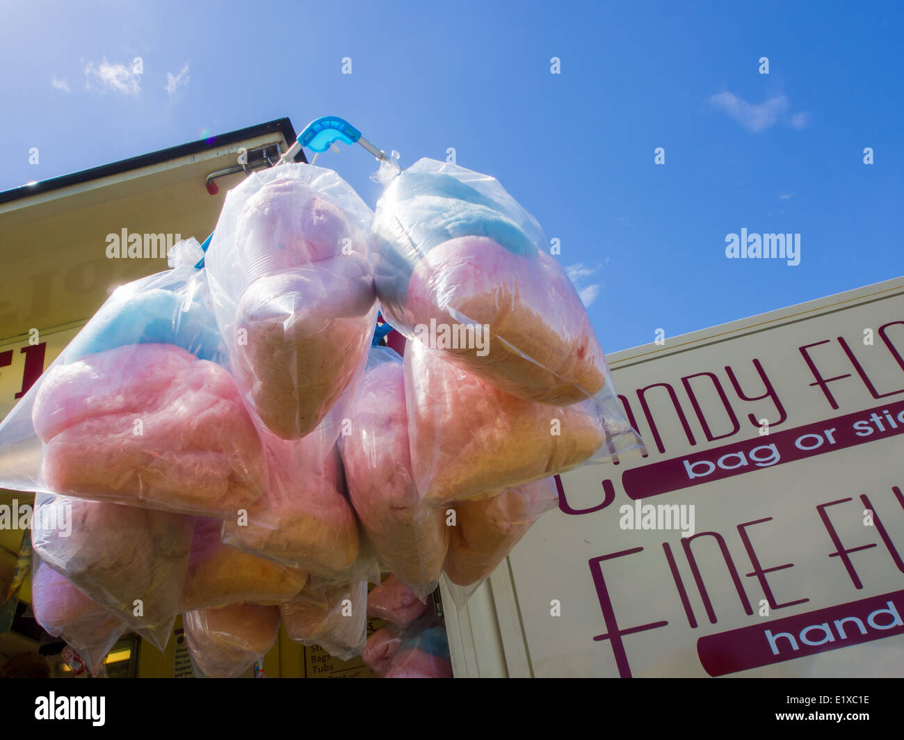Bags of candy floss on sale at a fairground stall and hanging against a blue sky Stock Photo