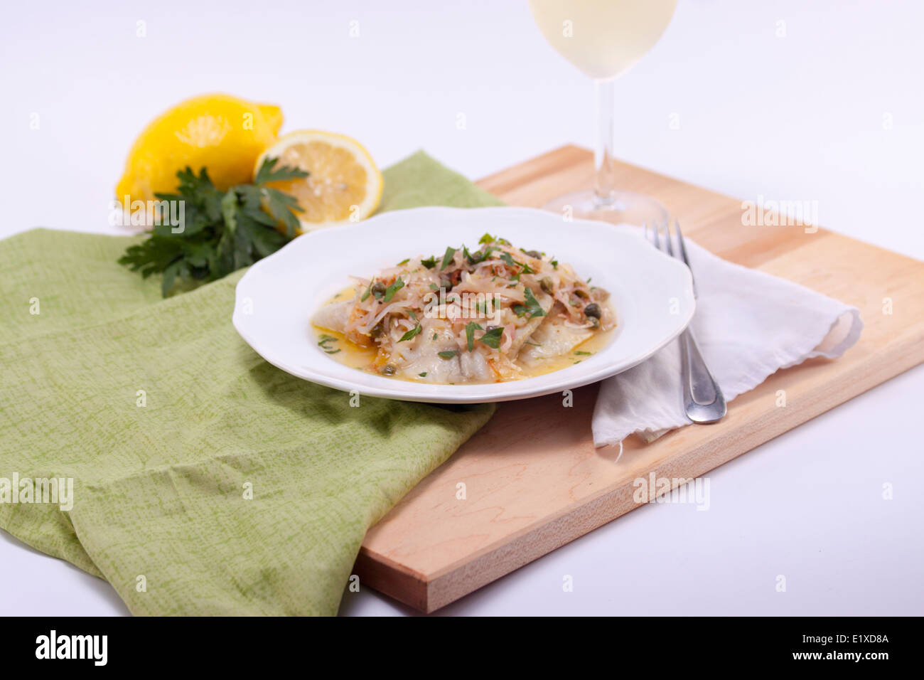 Tilapia, white fish, serving with caper sauce on cutting board. White