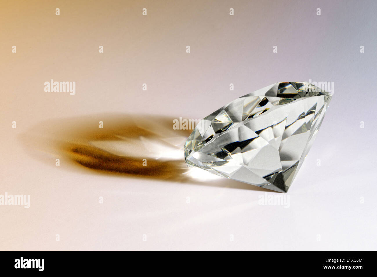 Faceted gemstone or diamond lying on its side on a white background casting an interesting shadow Stock Photo