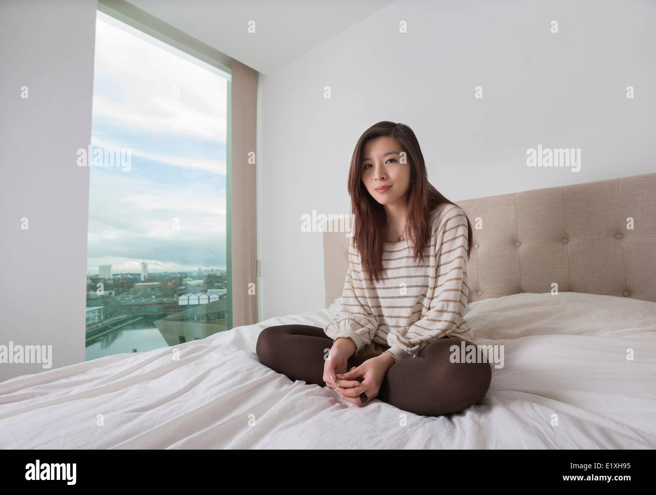 Portrait of beautiful young woman sitting on bed Stock Photo