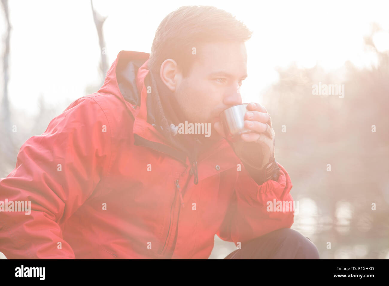 Male hiker drinking coffee in forest Stock Photo