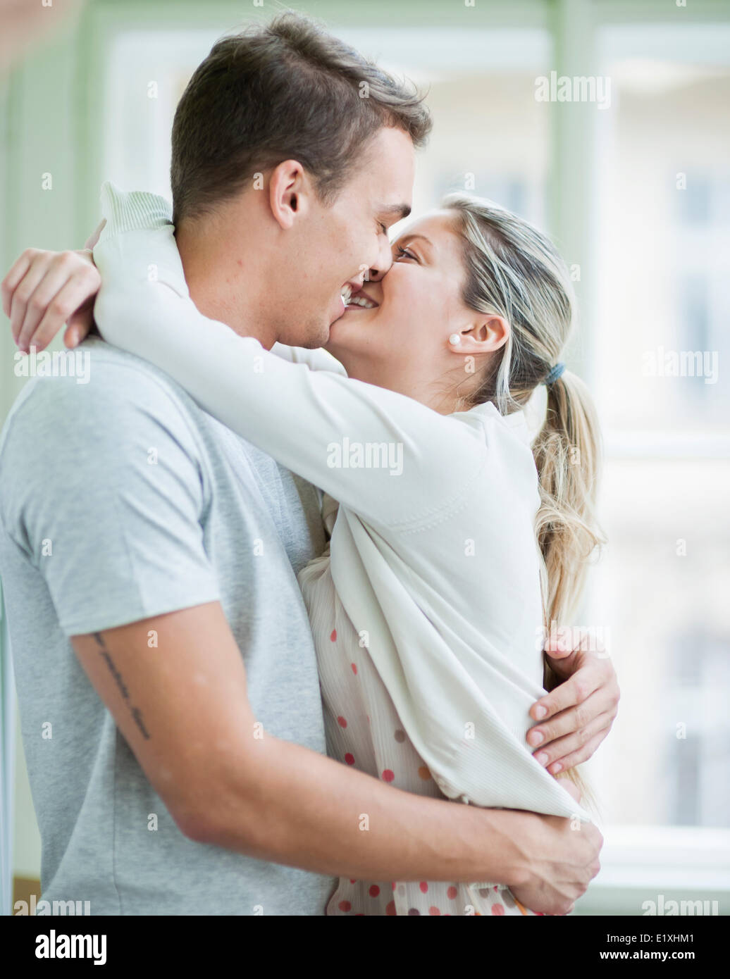 Loving couple kissing while hugging in house Stock Photo