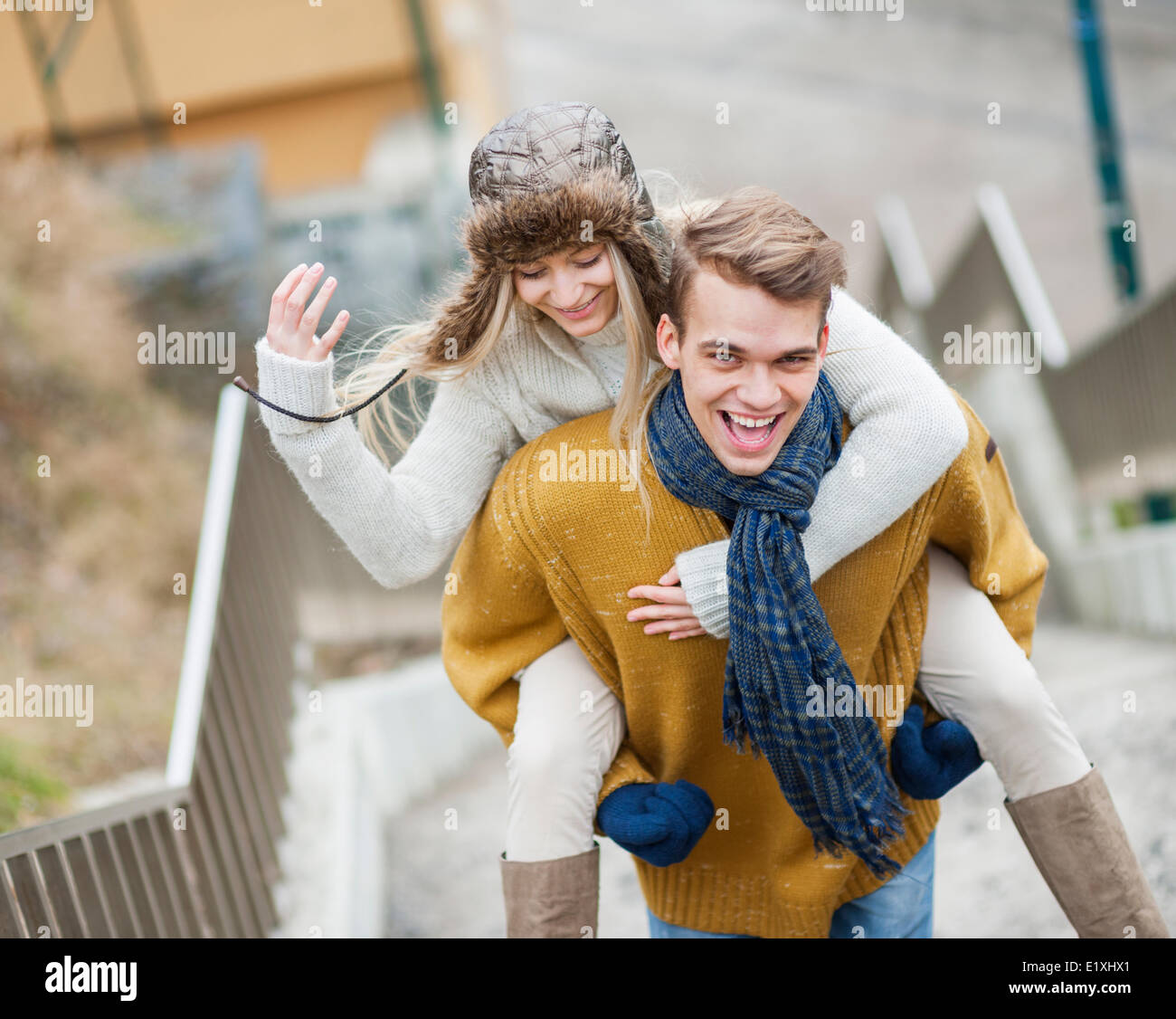 Portrait of cheerful man piggybacking woman on stairway Stock Photo