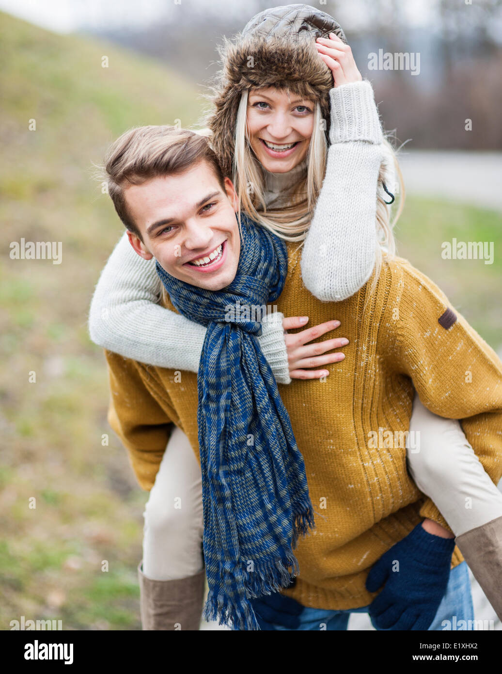 Portrait of happy man piggybacking woman in park Stock Photo