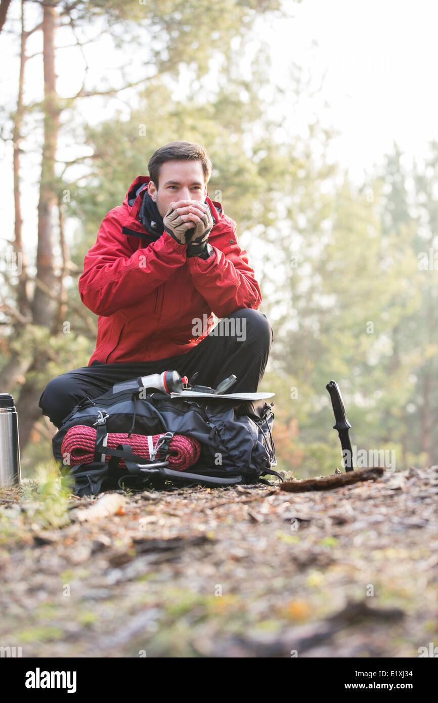 Male backpacker warming hands while looking away in forest Stock Photo