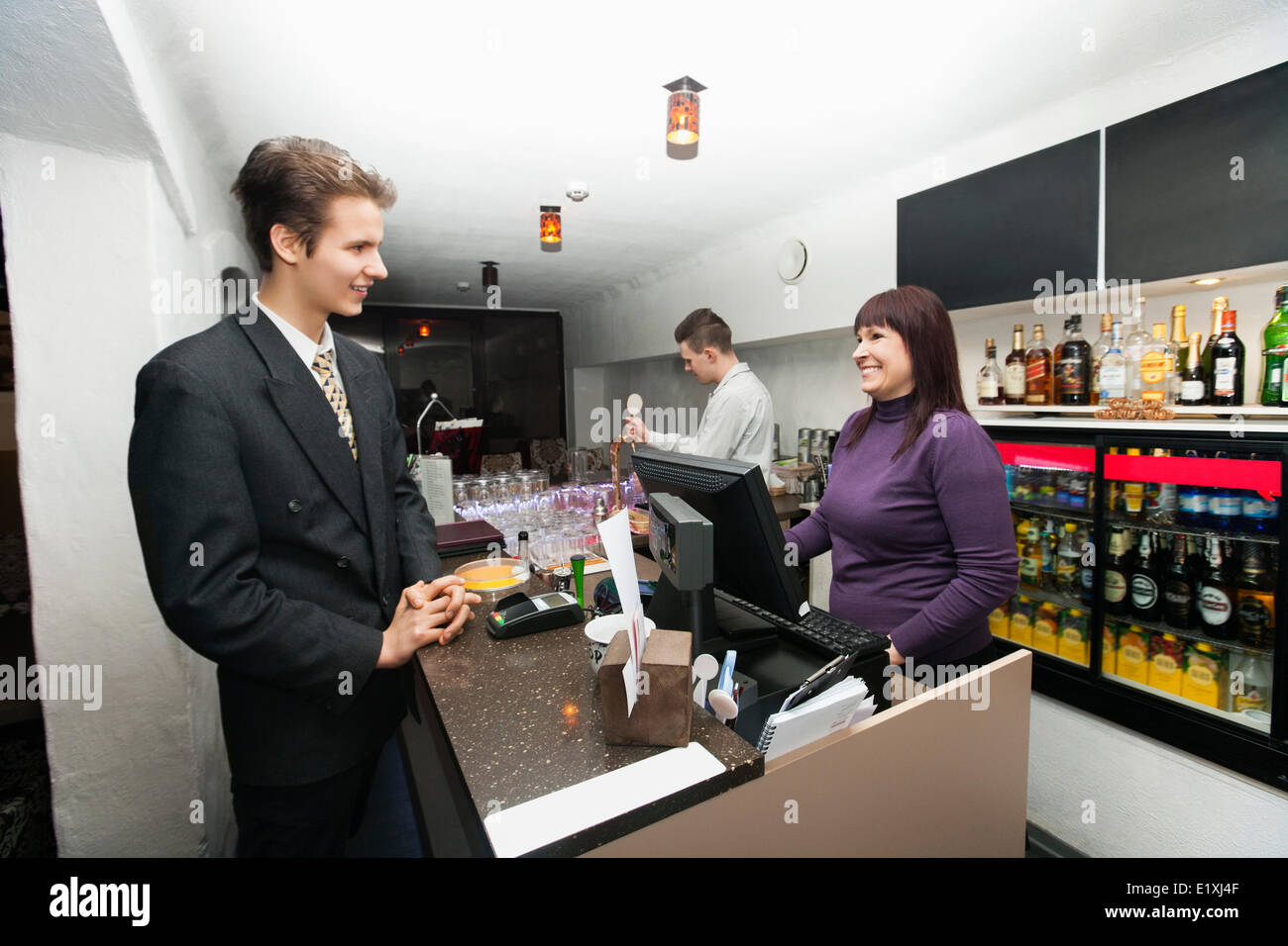 Manager communicating with cashier at bar counter Stock Photo