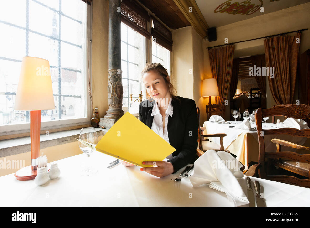 Beautiful customer reading menu at restaurant table Stock Photo - Alamy