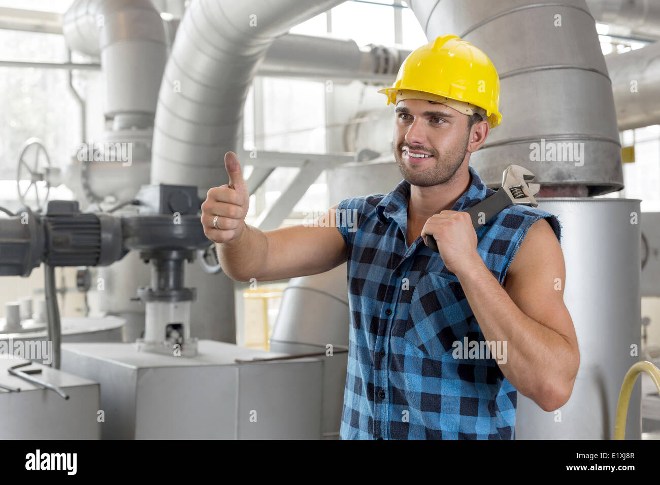 Handsome manual worker gesturing thumbs up in industry Stock Photo