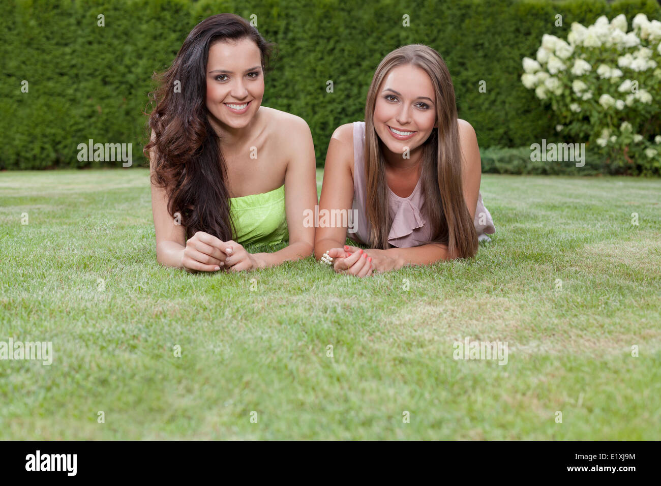 Portrait of beautiful young women with long hair lying in park Stock Photo