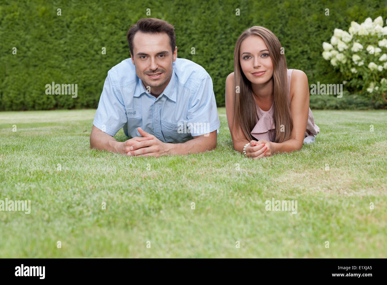 Portrait of happy young couple lying on grass in park Stock Photo - Alamy